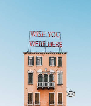 一間桃色酒店，帶有寫著 wish you were here 的紅色霓虹燈牌。 — Nubia Flip 壁紙