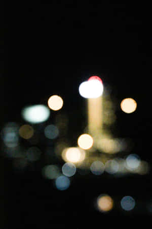 在城市環境中，黑暗夜空下柔和發光的散景燈光。