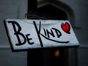 一個磨損的標牌，上面有「Be Kind」和一個紅色心形塗鴉。