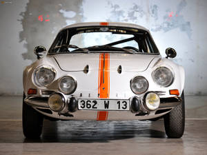 在混凝土車庫中，帶有橙色條紋的復古白色Alpine A110賽車。