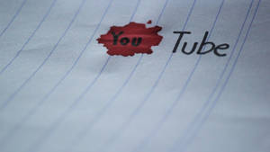 紅色墨跡遮蓋了橫線紙上YouTube標誌中的「You」。