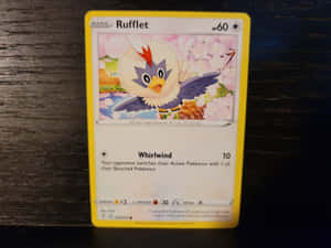 一張 Rufflet 寶可夢卡牌在深色木桌上，背景有櫻花。 — 遊戲 壁紙