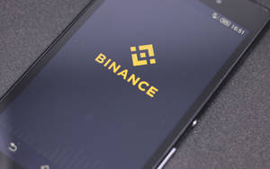 智能手機在深色屏幕上顯示 Binance 加密貨幣交易所標誌。 — 手機鎖定螢幕 壁紙