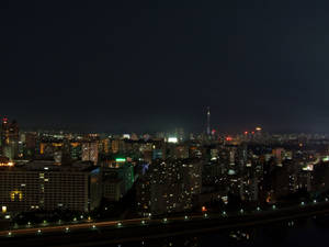 城市夜景，有明亮的建築物和下方的河流。