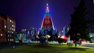 夜間城市環境中，一座明亮照明的金字塔建築帶有政治壁畫。