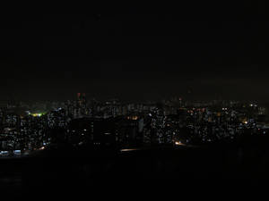 城市夜景，燈火通明的建築物映襯著黑暗的天空。