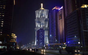 夜晚的城市景觀， featuring 一座頂部有金色雕像的發光摩天大樓。