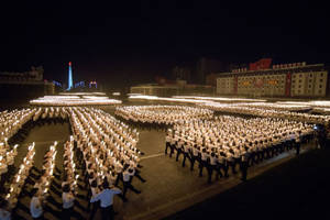一大群人在夜間手持點燃的蠟燭在城市廣場上遊行。