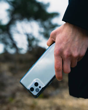 手在戶外拿著一部銀色 OPPO 手機，配備四鏡頭