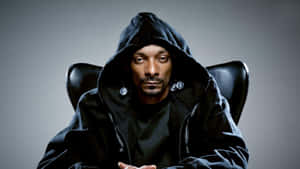 Snoop Dogg 身穿黑色連帽衫，戴著銀色耳環，坐在椅子上。