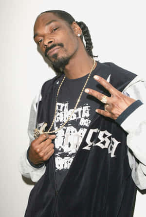Snoop Dogg 身穿黑色天鵝絨外套和金色鏈條，做出和平手勢。