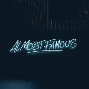 霓虹燈牌寫著「Almost Famous」，在黑暗的牆壁上發出藍光。