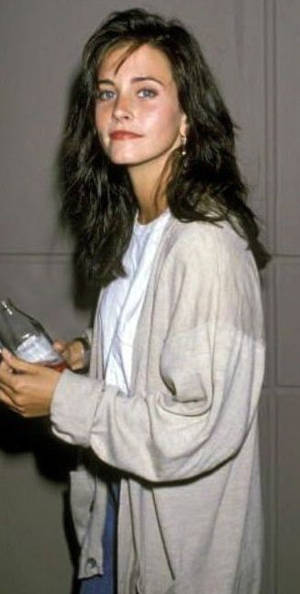 1990年代休閒裝扮的女性在室內手持玻璃瓶。