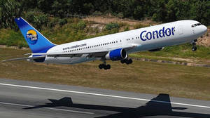Condor Thomas Cook飛機在綠色山丘背景下降落跑道。