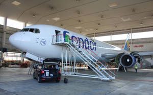一架Condor飛機停在機庫內，有流動樓梯和一輛汽車在附近。