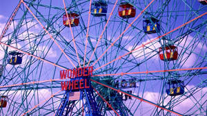暮色中帶有彩色纜車和美國國旗的 Wonder Wheel 遊樂園遊樂設施。