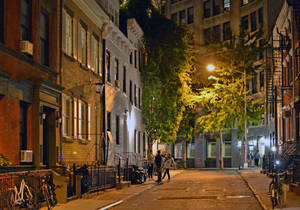 夜晚狹窄的城市小巷場景，有磚砌建築、樹木和行人。 — 夜景城市 壁紙