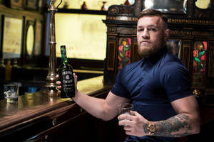 Conor McGregor 在華麗的酒吧手持威士忌酒瓶和酒杯，紋身清晰可見。
