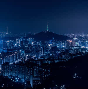 城市夜景，有發光的建築物和山上的點亮塔樓。 — iPad Pro 13 壁紙