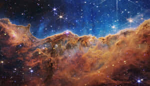 深空中點綴著明亮星星的鮮豔橙色星雲雲朵。 — iMac 壁紙