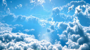 陽光穿過蓬鬆的白雲，照射在平靜的藍色海面上。 — 神之塔 壁紙