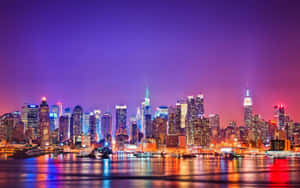 夜間城市天際線，發光的建築物在紫色天空下倒映在水中。