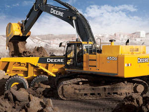 黃色 John Deere 挖掘機在建築工地將泥土裝載到自卸卡車上。