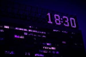 建築物上一個巨大的紫色數字時鐘在夜晚顯示18:30。