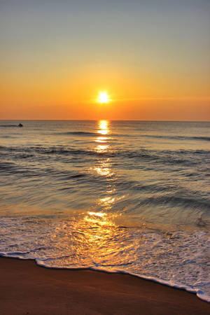 海上夕陽，沙灘上的海浪，遠處的游泳者 — 海洋 壁紙