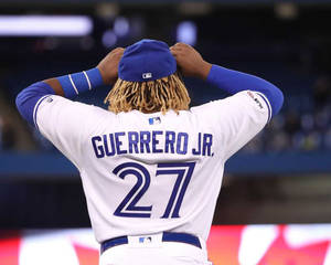 棒球手 Guerrero Jr. 在明亮的球場上調整他的帽子。
