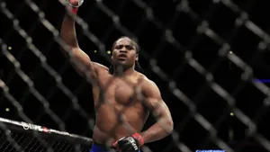 UFC拳手在八角籠內舉起拳頭慶祝勝利。