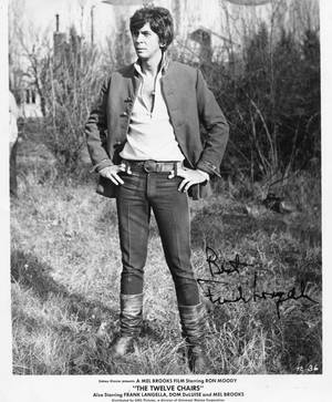 Ron Moody 在電影劇照中穿著外套和靴子站在草地上。 — 電影 壁紙