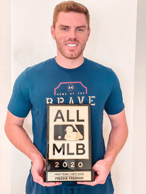 棒球運動員Freddie Freeman在室內舉起他的2020年全MLB第一隊獎盃。