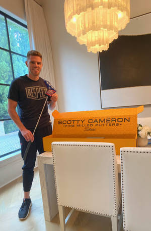 男人在現代餐廳裡拿著高爾夫推桿，旁邊有Scotty Cameron推桿盒。