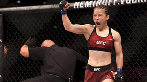 女性MMA拳手在UFC八角籠中高舉拳頭慶祝勝利。