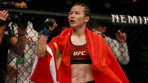 女MMA拳手披紅旗在UFC八角籠慶祝勝利。