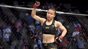 女性MMA拳手在UFC八角籠中高舉拳頭慶祝勝利。