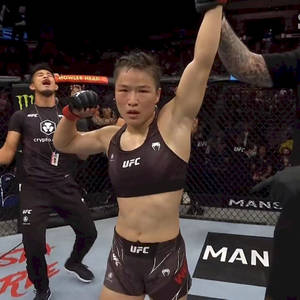 女性MMA拳手在UFC八角籠中與教練慶祝勝利。