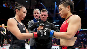 兩名女子MMA拳手在場館燈光下於UFC比賽前碰拳套。