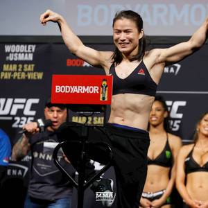 女性MMA拳手在UFC過磅活動中微笑並展示肌肉。