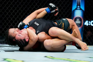 兩名女拳手在MMA籠內陷入纏鬥。