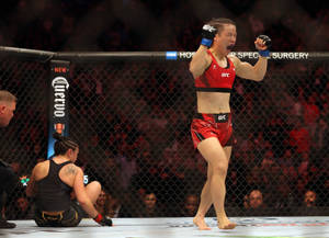 女性MMA拳手在擊敗對手後於八角籠中慶祝勝利。