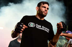 運動員戴著黑色手套，穿著Oak Grove Technologies襯衫，在煙霧繚繞的競技場中。 — 3:2 壁紙