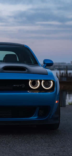 藍色Dodge Challenger SRT Hellcat，在黃昏時分帶有發光的頭燈。