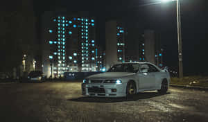白色跑車停在夜間濕潤的城市街道上，在街燈下。 — 日產 Skyline GTR R33 壁紙