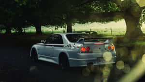 白色跑車停泊在樹下，伴隨著發光的散景燈光。 — 日產 Skyline GTR R33 壁紙