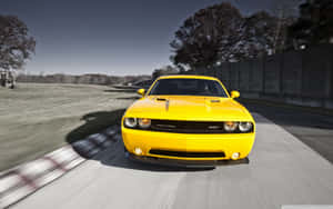 黃色 Dodge Challenger SRT 在賽道上高速行駛，帶有動態模糊效果。