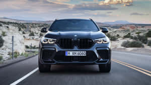 黑色BMW SUV在日落時分行駛在沙漠公路上 — 寶馬X6 M 壁紙
