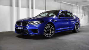 光澤的藍色BMW M5房車停在一個混凝土車庫中，帶有白色柱子。
