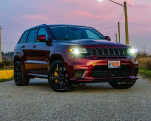 栗色Jeep Trackhawk，黑色輪圈和黃色制動，黃昏時停泊在礫石上。